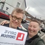 Drive Croydon learner standing beside an automatic driving school car